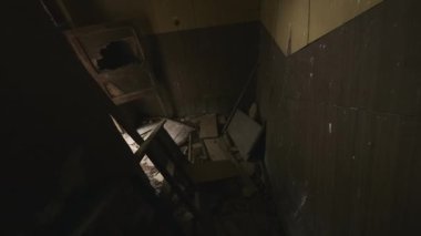 Yıpranmış merdivenlerden inerken çekilen el kamerası görüntüsü. Çürüyen binanın dış terasına çıkılıyor.