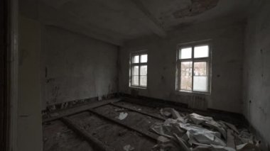 Pan right interior of spacious room with opened window and wooden floor inside of aged desolate building viewing woods