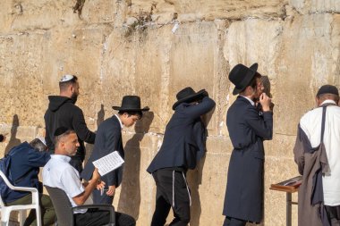 Tel Aviv, İsrail - 22 Kasım 2022: Kudüs 'te Ağlama Duvarı' na bakarken ayakta duran ve sandalyelerde oturan Yahudi erkeklerin arka planı