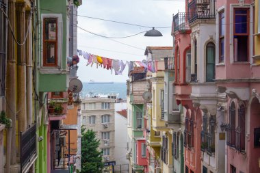 Bulutlu bir günde mavi denize karşı ipte kuruyan balkonları ve giysileri olan renkli konutların dış yüzeyi.