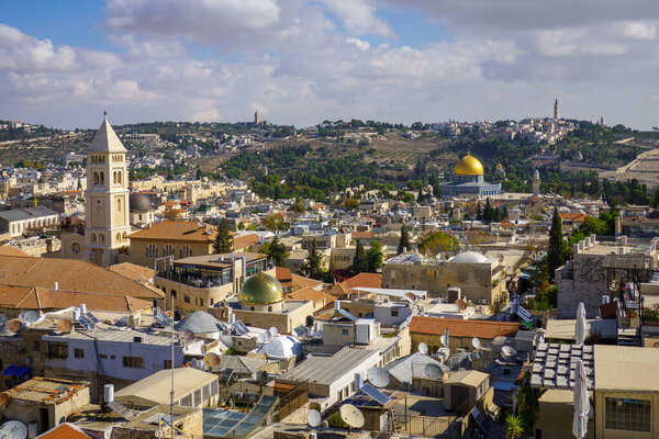 Живописный вид на старые исторические храмы и церкви, расположенные в древнем районе Иерусалима со зданиями и зелеными деревьями под облачным небом