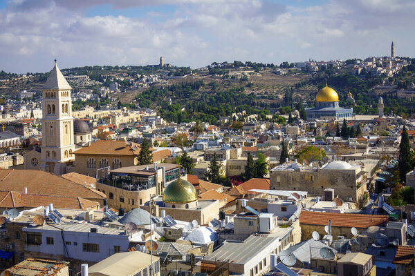Живописный вид на старые исторические храмы и церкви, расположенные в древнем районе Иерусалима со зданиями и зелеными деревьями под облачным небом