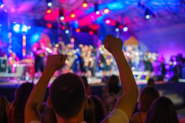 Sahnede parlayan ışıklarla duran ve gece vakti kalabalığın fotoğrafını çeken tanınmamış insanların arka plan görüntüsü.