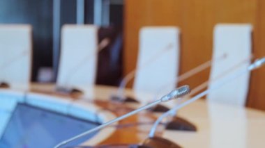 Modern konferans odasının sağ seçici odağı beyaz sandalyeler ahşap masa ve ofis binasında gri küçük mikrofonlar.