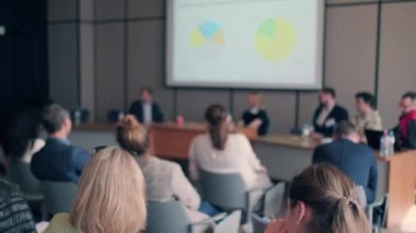 İş semineri sırasında muhabirlerin önünde masalarda oturup finansal sunum yapan resmi resmi el kamerasıyla çeken hoparlörler.