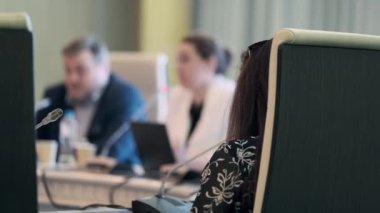 İş arkadaşlarının toplantı sırasında mikrofonlarla konferans masasında toplanıp iş stratejilerini tartışırken, bayan çalışanların akıllı telefondan fotoğraf çektikleri yumuşak bir odaklanma..