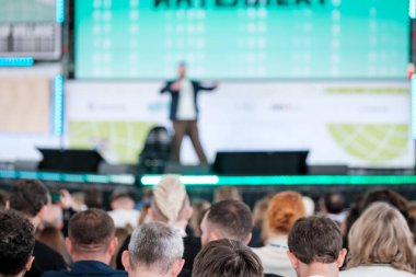 Geçmişteki konferans salonunda tanımadığımız şık kıyafetlerle oturan ve slaytlarla sunum yapan hocaların arka planda bulanık arka planda oturduğunu görüyoruz.