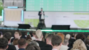 Erkek konuşmacının sahnede yürürken, mikrofona konuşurken, insanlara ilham verirken ve konferans sırasında motivasyon konuşması yaparken,