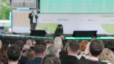 Erkek konuşmacının sahnede yürürken, mikrofona konuşurken, insanlara ilham verirken ve konferans sırasında motivasyon konuşması yaparken,