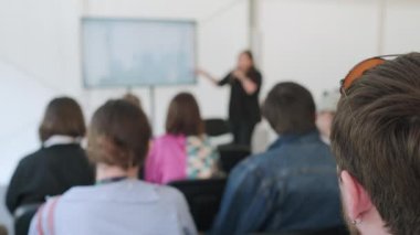 Seminer sırasında mikrofona ve jestlere konuşma yapan insanların sahnede sunum yaptığı gerçek zamanlı görüntüler.