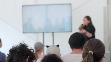 Seminer sırasında mikrofona ve jestlere konuşma yapan insanların sahnede sunum yaptığı gerçek zamanlı görüntüler.