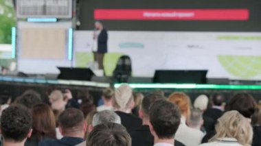 Erkek konuşmacının sahnede yürürken, mikrofona konuşurken, insanlara ilham verirken ve konferans sırasında motivasyon konuşması yaparken,