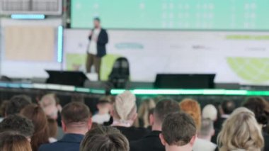 Erkek konuşmacının sahnede yürürken, mikrofona konuşurken, insanlara ilham verirken ve konferans sırasında motivasyon konuşması yaparken,