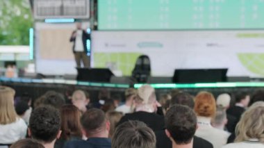 Erkek konuşmacının sahnede yürürken, mikrofona konuşurken, insanlara ilham verirken ve konferans sırasında motivasyon konuşması yaparken,