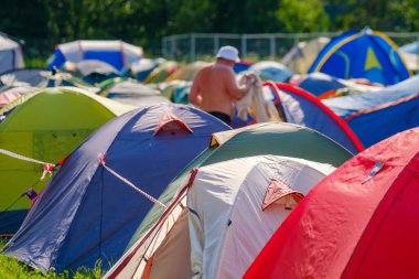 Güneşli bir günde müzik festivali sırasında kamp alanında renkli çadırlar kuruldu.