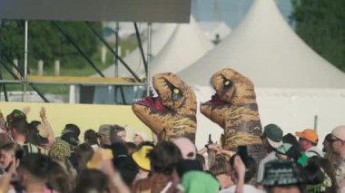 Moskova - 16 Haziran 2023: Gerçek zamanlı izleyiciler ve açık hava müzik festivali sırasında dans eden şişme dinozor kostümleri giyen insanlar güneşli yaz haftasonunda eğleniyorlar
