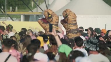 Moskova - 16 Haziran 2023: Gerçek zamanlı izleyiciler ve açık hava müzik festivali sırasında dans eden şişme dinozor kostümleri giyen insanlar güneşli yaz haftasonunda eğleniyorlar