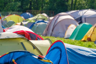 Güneşli bir günde müzik festivali sırasında kamp alanında renkli çadırlar kuruldu.