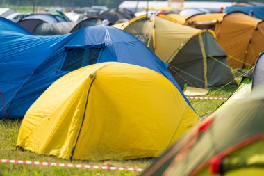 Güneşli bir günde müzik festivali sırasında kamp alanında renkli çadırlar kuruldu.