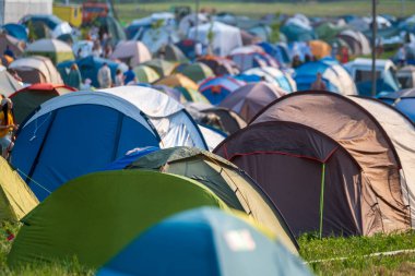 Güneşli bir günde müzik festivali sırasında kamp alanında renkli çadırlar kuruldu.