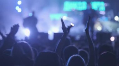 Mavi neon ışıklarıyla sahnede müzik dinleyen insanların arka planı
