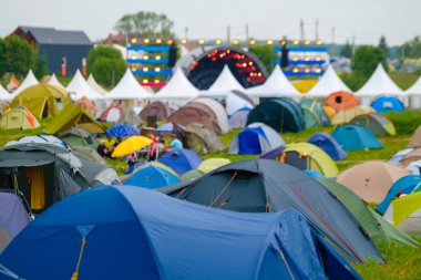 Müzik festivali sırasında arka planda parlayan sahne ile kamp alanında parlak çadırlar kurun