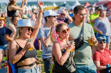 Moskova - 13 Haziran 2023: Bir grup havalı kadın ve erkekler gün ışığında festivalde müzik dinlerken plastik bardak içiyorlar