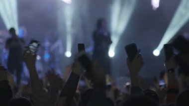 Konserde müzik grubunun performansını dinlerken cep telefonlu müzik hayranlarının arka plan görüntüsü