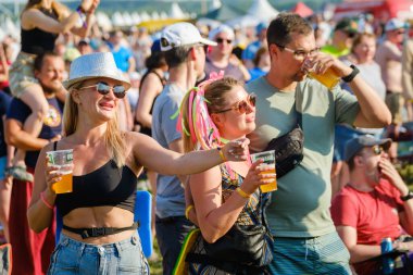 Moskova - 13 Haziran 2023: Bir grup havalı kadın ve erkekler gün ışığında festivalde müzik dinlerken plastik bardak içiyorlar