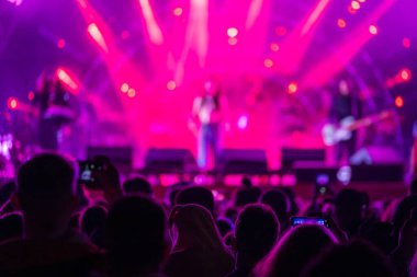 Sahne yakınındaki bir grup hayran ve gece parlayan kırmızı spot ışıklarıyla müzik grubu