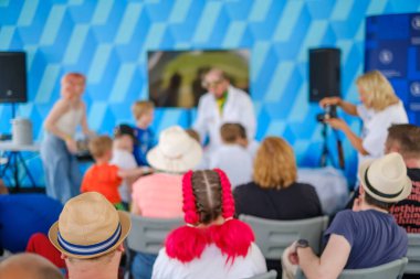 Modern gençlerin erkek bilim sanatçılarının önünde oturup meraklı çocuklarla canlı yayında numaralar göstermesi.