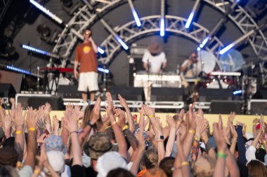 Sahnede müzik grubunu selamlayan ve konserin tadını çıkaran insanların kollarını kaldırdı.