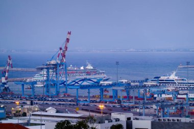 Modern yolcu gemileri Haifa İsrail 'de mavi gökyüzüne karşı konteynır vinçleriyle dalgalanan denize demirlediler.
