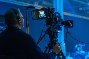 Aydınlanmış konferans salonunda küresel semineri kaydeden erkek videografın arka görüntüsü 