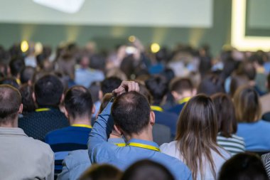 İş adamlarının, konferans salonundaki meslektaşlarıyla küresel sunuma katılırken kafa kafaya oturdukları arka plan 