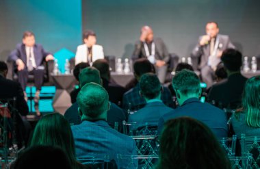 Attendees focus on speakers during business conference panel discussion with emphasis on engagement and networking. clipart