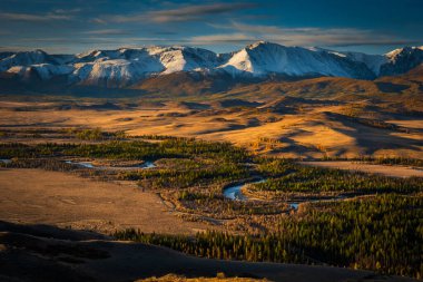 Altai dağlarının göz kamaştırıcı sonbahar manzarası altın ovaları ve dolambaçlı nehirleri dramatik bir günbatımı gökyüzü altında.