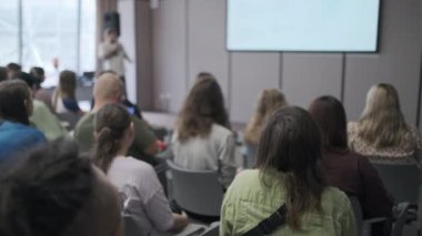 Diverse group of people paying attention to a presenter in a conference setting. Educational and informative atmosphere with engaged audience and speaker.