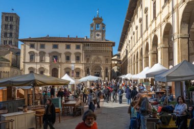 Arezzo, İtalya - 2 Kasım 2024: Ziyaretçiler, Arezzo tarihi merkezindeki aylık pazarda, sokak ve meydanlar boyunca satıcıların sergilediği eşyaları araştırarak antikalara göz atıyor