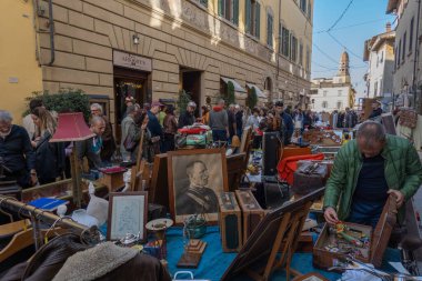 Arezzo, İtalya - 2 Kasım 2024: Ziyaretçiler, Arezzo tarihi merkezindeki aylık pazarda, sokak ve meydanlar boyunca satıcıların sergilediği eşyaları araştırarak antikalara göz atıyor