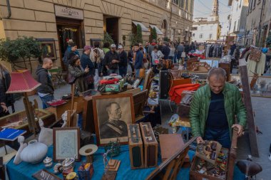 Arezzo, İtalya - 2 Kasım 2024: Ziyaretçiler, Arezzo tarihi merkezindeki aylık pazarda, sokak ve meydanlar boyunca satıcıların sergilediği eşyaları araştırarak antikalara göz atıyor