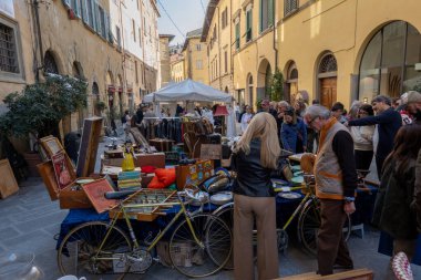 Arezzo, İtalya - 2 Kasım 2024: Ziyaretçiler, Arezzo tarihi merkezindeki aylık pazarda, sokak ve meydanlar boyunca satıcıların sergilediği eşyaları araştırarak antikalara göz atıyor
