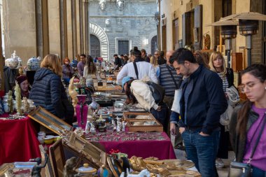 Arezzo, İtalya - 2 Kasım 2024: Ziyaretçiler, Arezzo tarihi merkezindeki aylık pazarda, sokak ve meydanlar boyunca satıcıların sergilediği eşyaları araştırarak antikalara göz atıyor