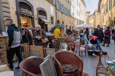 Arezzo, İtalya - 2 Kasım 2024: Ziyaretçiler, Arezzo tarihi merkezindeki aylık pazarda, sokak ve meydanlar boyunca satıcıların sergilediği eşyaları araştırarak antikalara göz atıyor