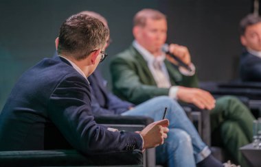 Profesyoneller iş konferansında bir panel tartışmasına katılırlar. Odaklanmış diyalog, endüstri bağlamında işbirliği ve anlayışı vurguluyor.