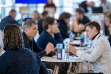 İş dünyasından profesyoneller tartışmalara giriyor, ağ oluşturma etkinliğinde fikirlerini paylaşıyorlar. Bulanık arkaplan, modern kurumsal ortamda etkileşime, işbirliğine ve takım çalışmasına odaklanma yaratır.