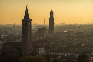 Günbatımında Verona 'nın çarpıcı manzarası, tarihi kuleler ve sıcak, altın bir gökyüzünün altında genişleyen bir şehir manzarası..