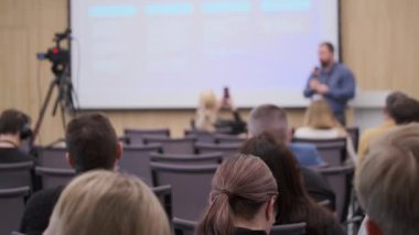 Hoparlörlerin sunduğu ve dinleyicilerin dinlediği iş seminerinin ön görüntüsü bulanık.