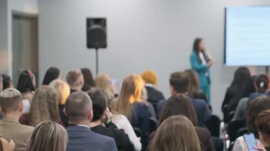 Odaklanmış seyirciler, profesyonel konferansta sunumla birlikte konuşmacıları dinliyorlar..