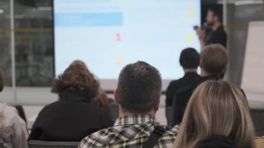 Kurumsal seminer sırasında insanlar sunum ekranının önünde oturuyordu. Profesyonel ayar meşgul dinleyicileri gösteriyor, mikrofonlu hoparlör.